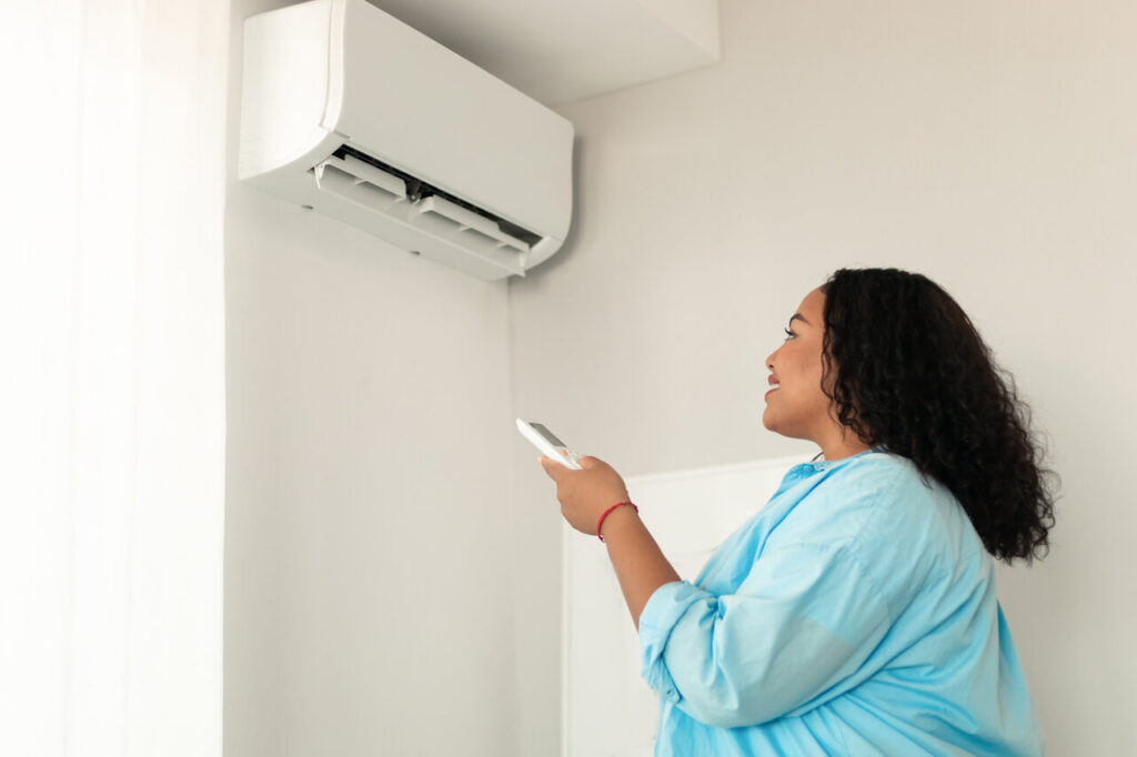 rsz african american woman turning on air conditioner 2023 11 27 05 18 53 utc